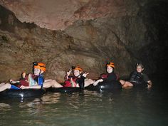 four people sitting on inflatable rafts inside a cave