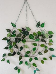 a metal wall hanging with green leaves on it