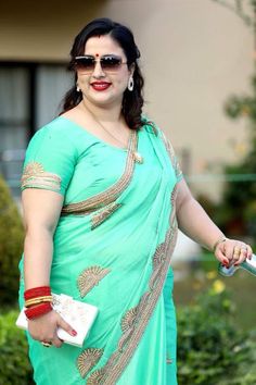 a woman in a green sari holding a white purse