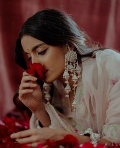 a woman laying on the ground holding a flower in her hand and smelling it with both hands