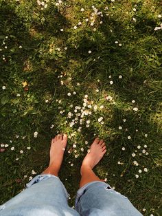 a person standing in the grass with their feet up and flowers on the ground behind them