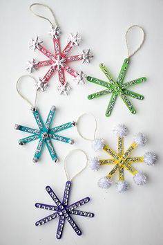 four snowflake ornaments are hanging on a white surface with string attached to them