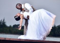 a bride and groom are kissing on the dock