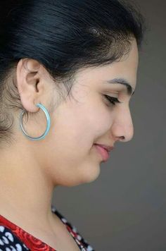 a woman with black hair wearing large hoop earrings