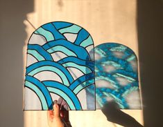 someone is holding up a stained glass piece to show it's shape and color