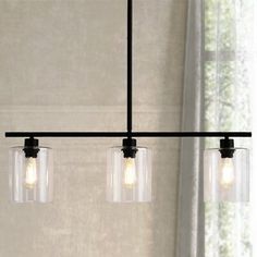 three lights that are hanging from a light fixture in a room with curtains and windows