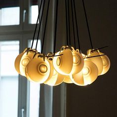 a chandelier with five lights hanging from it's sides in front of a window