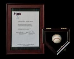 a framed baseball and certificate in a wooden frame on a black background next to an award plaque