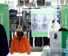 an orange jacket is on display in a clothing store while people look at the items