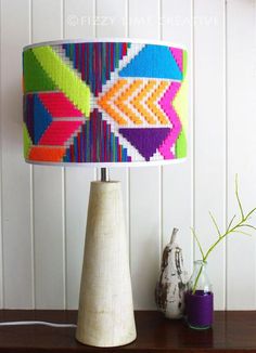 a colorful lamp is sitting on a table next to a vase and potted plant