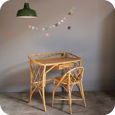 a wooden table with two chairs under a green light hanging from the ceiling above it