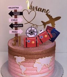 a pink and gold birthday cake with luggage on it's top, labeled in spanish