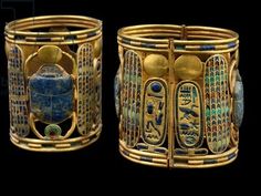 two gold bracelets with egyptian writing on them