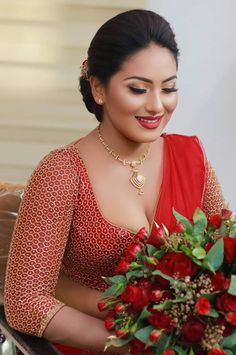 a woman in a red sari holding a bouquet of flowers