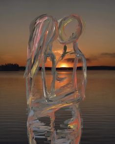 a glass sculpture sitting on top of a body of water at sunset with the sun in the background