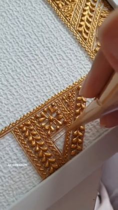 someone is working with gold thread on a piece of fabric that has been stitched together