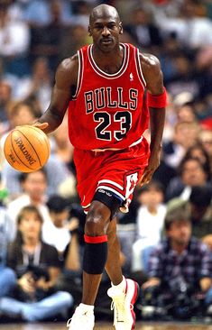 a basketball player dribbles the ball during a game in front of an audience