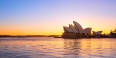 the sydney opera house is lit up at sunset