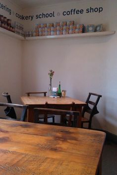 there is a wooden table and chairs in the corner of this room with shelves on the wall