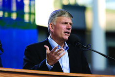 a man in a suit and tie speaking into a microphone