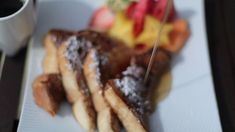 a white plate topped with french toast and fruit