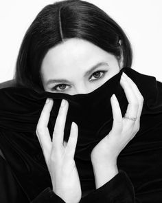 black and white photograph of a woman covering her face with a scarf over her head