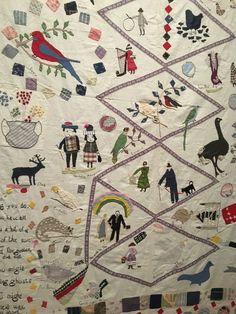 a large quilt with people and animals on it's sides, all hand written in different languages