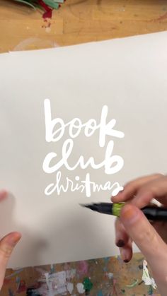 two hands holding scissors over a piece of paper with the words book club christmas written on it