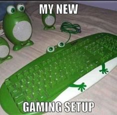 a green computer keyboard sitting on top of a bed next to two little frog figurines
