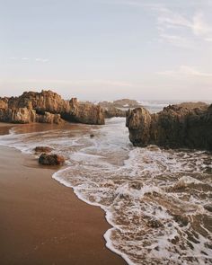 an ocean beach with waves coming in to shore and rocks sticking out of the water