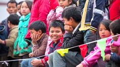 a group of young children sitting next to each other on top of a field with kites