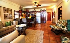 a living room filled with furniture next to a kitchen and dining room table in front of a refrigerator