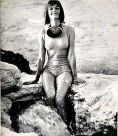 a woman in a bathing suit sitting on rocks