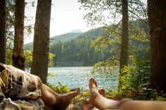 a person laying on a blanket in the woods with their feet up next to each other