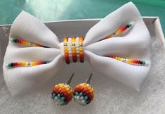 three pieces of colorful beaded bow tie and earring set in a white box