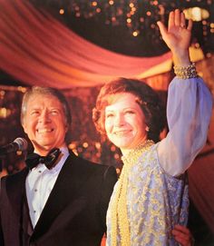 a man and woman standing next to each other in front of a microphone on stage