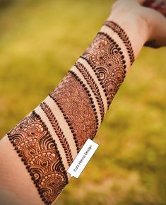 a woman's arm with henna tattoos on it and a name tag attached to the arm