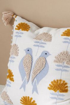 a decorative pillow with two birds on it