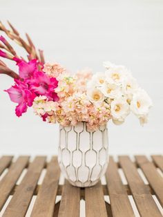 a white vase filled with pink and white flowers