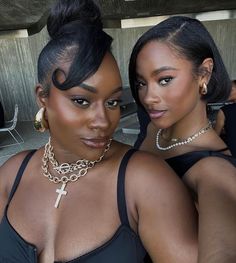 two women in black dresses posing for the camera with gold chains around their neck and cross necklaces on