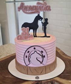 there is a pink cake with a horse on it and an animal sign above the top