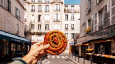 a person holding up a piece of food in the middle of a street