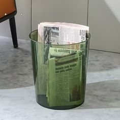 a trash can with newspapers in it sitting on the floor