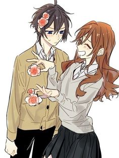 two people standing next to each other with flowers in their hair and one person pointing at the