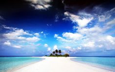 an island in the middle of some water with palm trees on one side and clouds in the other