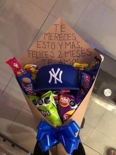 a bouquet of candy wrapped in paper with a baseball cap and new york yankees hat on top