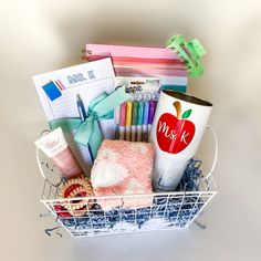 a basket filled with lots of school supplies on top of a white table next to a cup