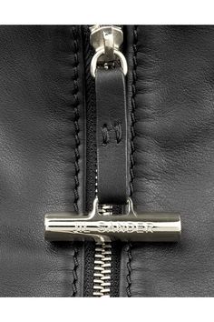 the zipper on a black leather jacket that is zipped open and has a silver metal handle