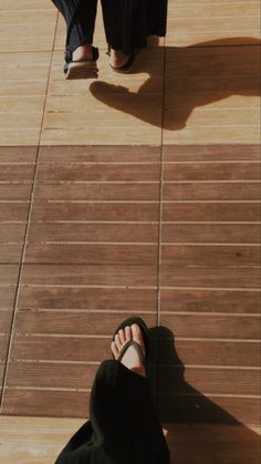 two people standing on a wooden floor next to each other with their feet up in the air