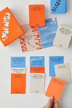 several different colored business cards being held by a person's hand on a white surface